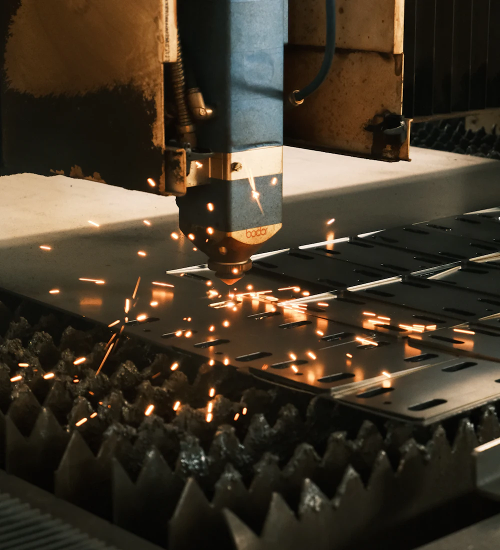A machine cutting a metal sheet with sparks flying